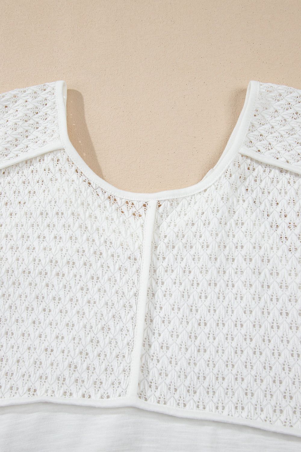 White lace-inset dolman sleeve blouse with a scoop neckline and open knit detail.