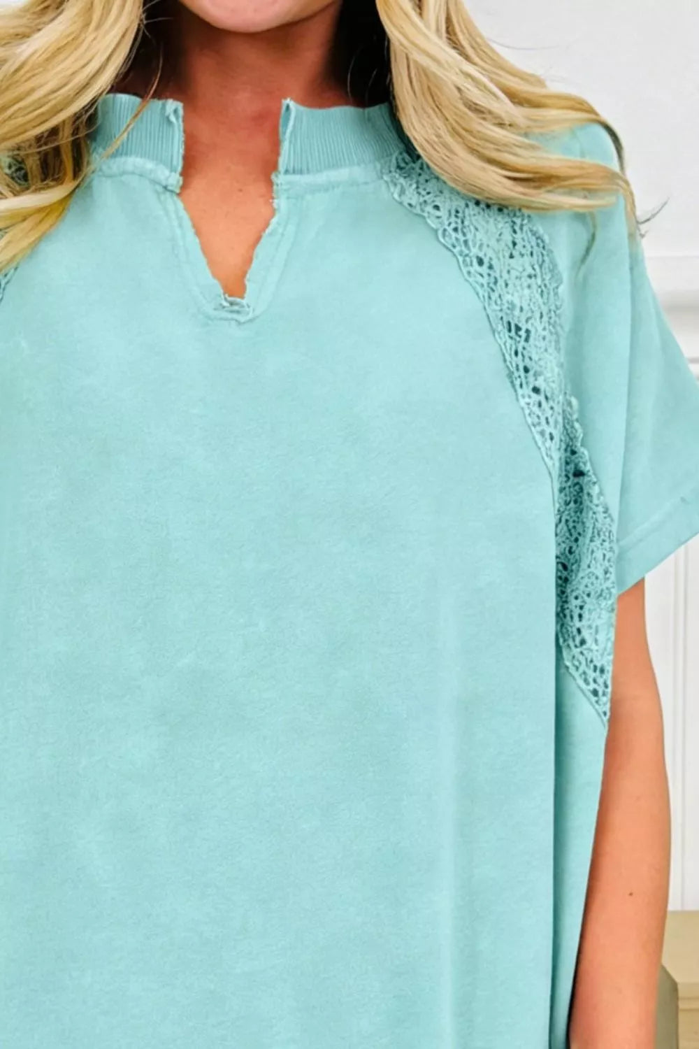 Distressed teal cotton tee with notched V-neck and lace shoulder detail.