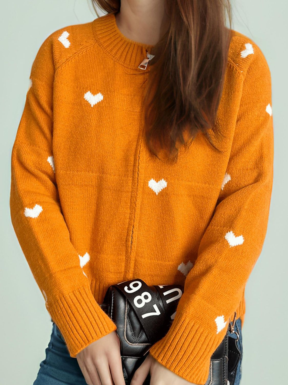 Tangerine zip-through knit sweater with white heart appliqué and ribbed cuffs.