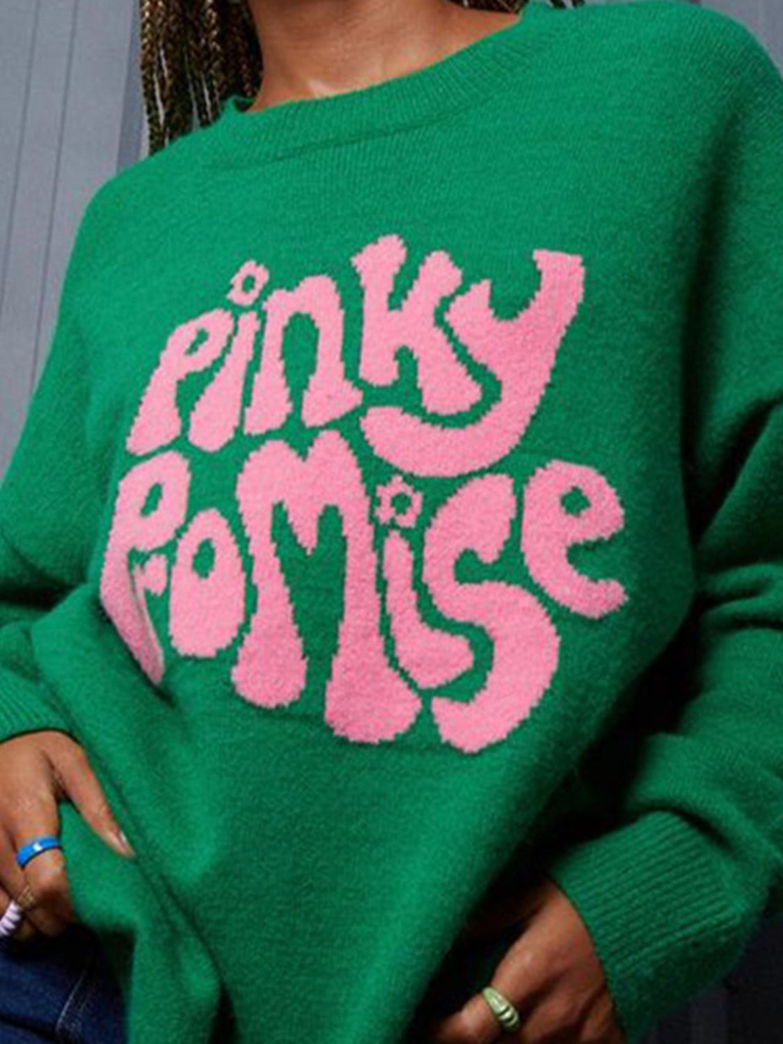 Green knit sweater with pink "Pinky Promise" graphic text and crew neck.