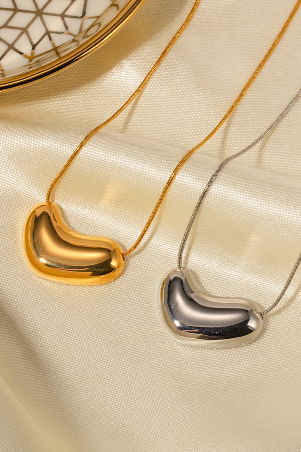 Gold and silver bean-shaped sculptural pendant necklaces with snake chains