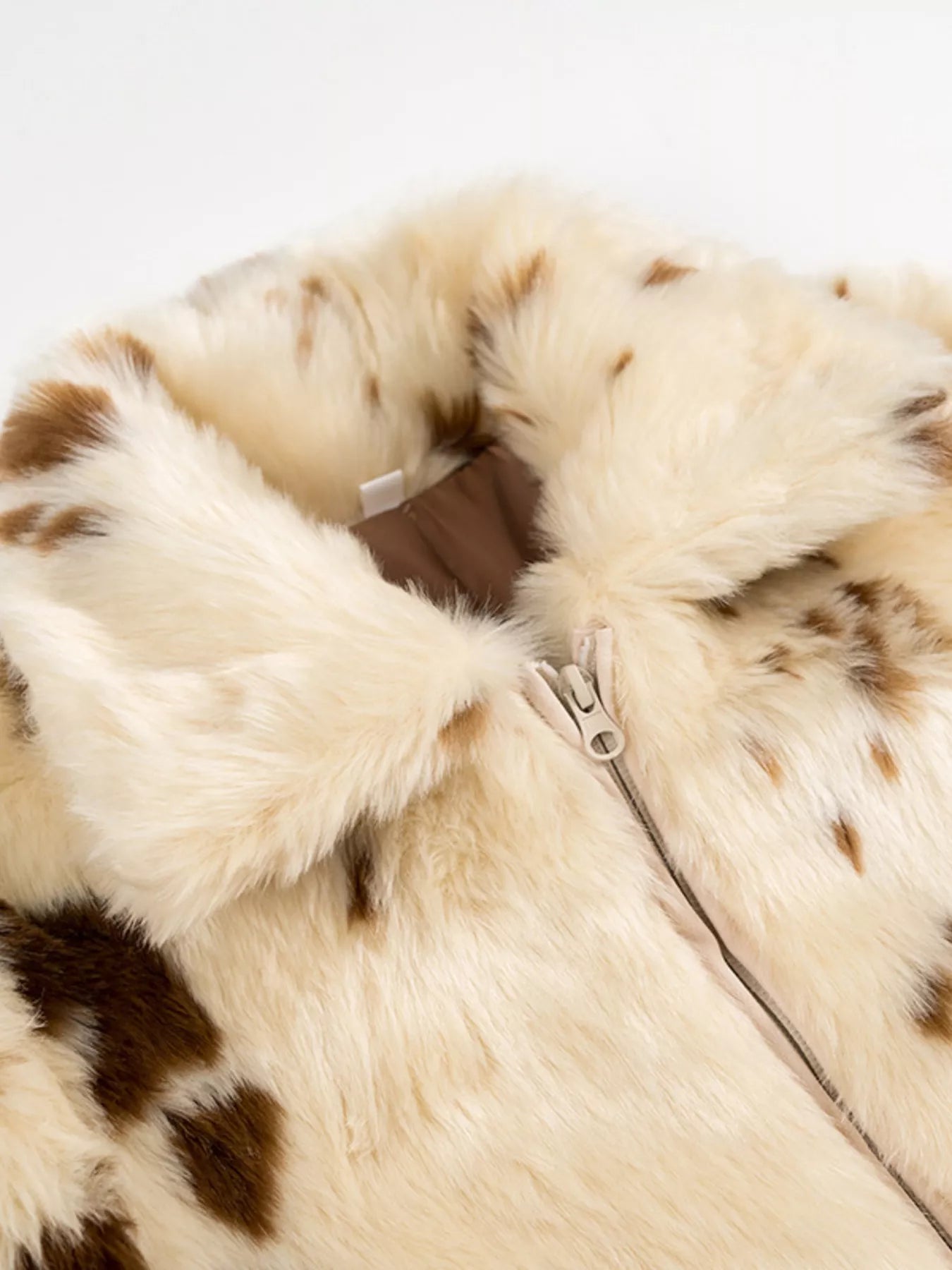 Cropped faux fur zip up jacket in beige with brown spots and a cream zipper.