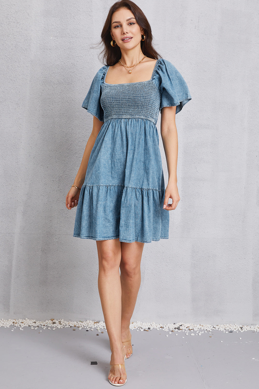 Light denim prairie dress with smocked bodice, puff sleeves, and tiered skirt.