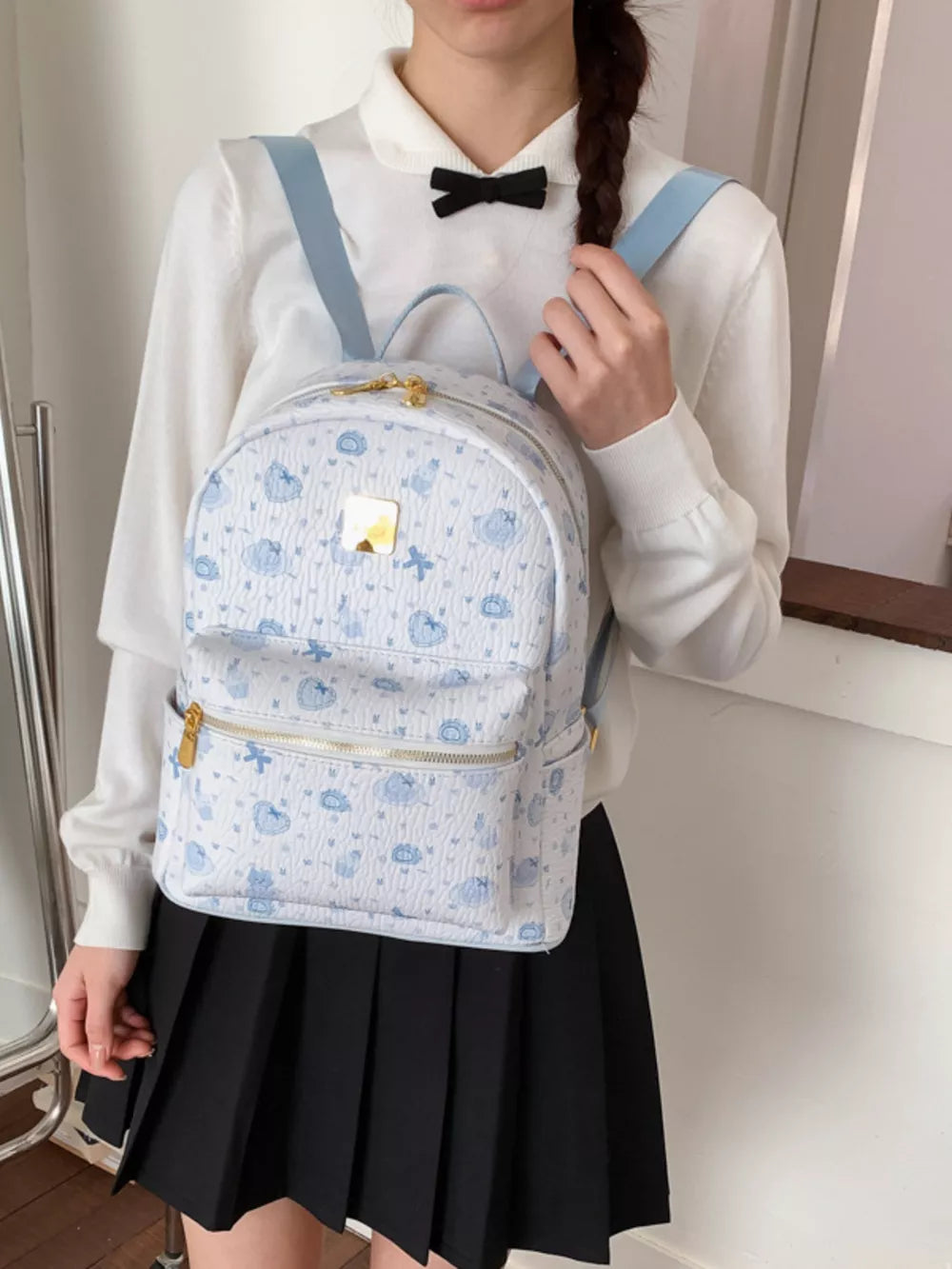 Charming mini backpack in blue with playful motifs and gold zipper details.