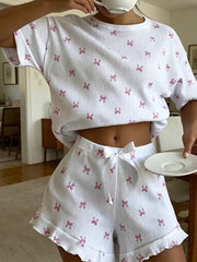 White knit lounge set with pink bow print, cropped t-shirt and ruffled shorts with drawstring.
