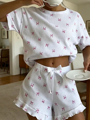 White knit lounge set with pink bow print, cropped t-shirt and ruffled shorts with drawstring.