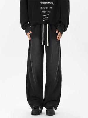 Black relaxed fit wide-leg jeans with white drawstring detail and subtle stripe accent.