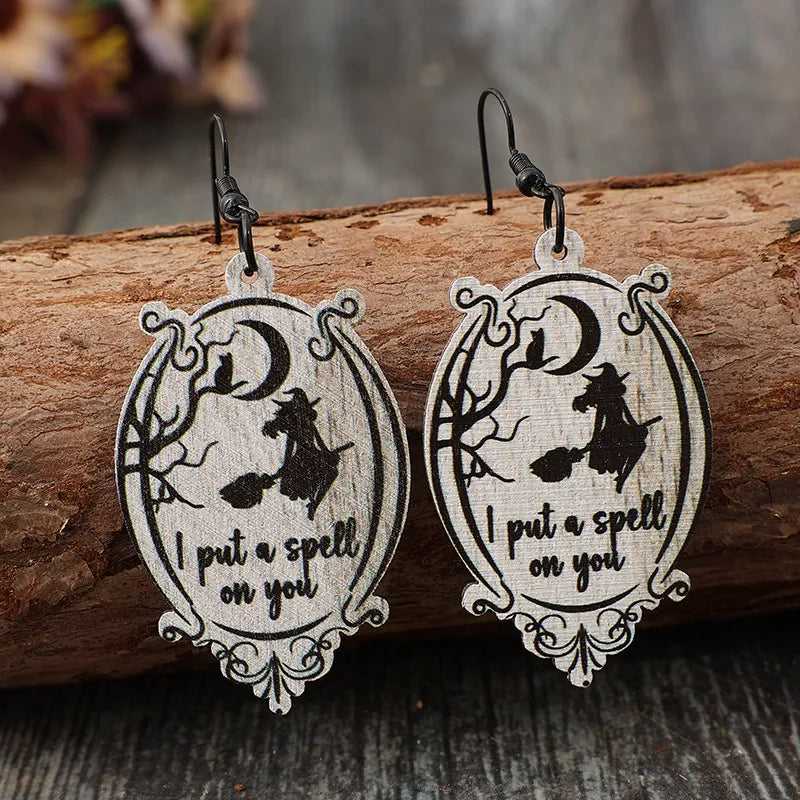 Black wood drop earrings with witch, cat, moon, and spell text.