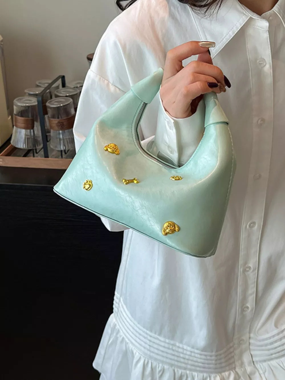 Pastel yellow hobo bag with gold accents and a textured finish.