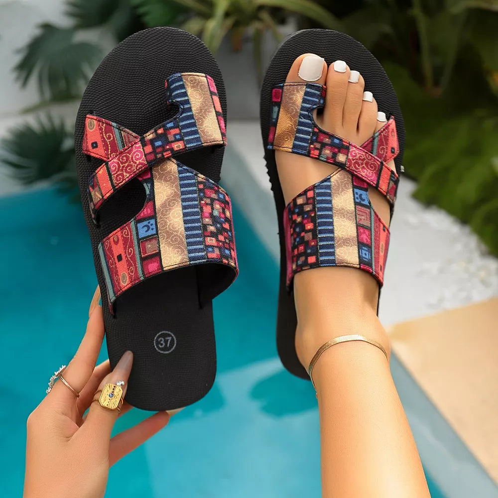 Geometric patterned toe loop sandals with colorful crisscross straps and black soles.