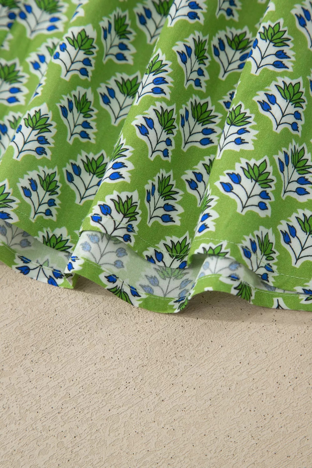 Floral tie-strap tank top with square neckline in green cotton with blue and white floral print.
