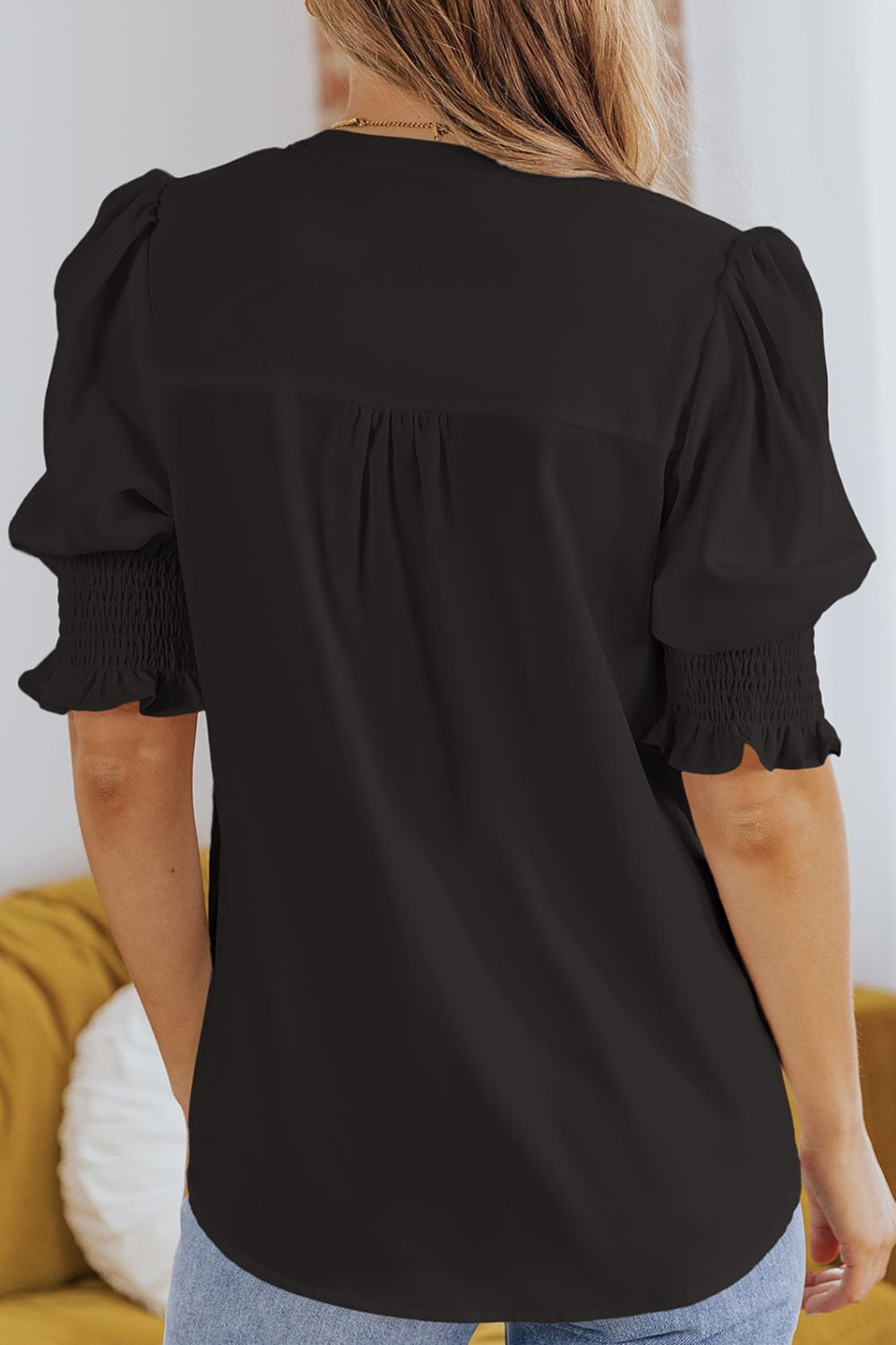 Black puff sleeve blouse with smocking detail on cuffs and gathered back yoke.
