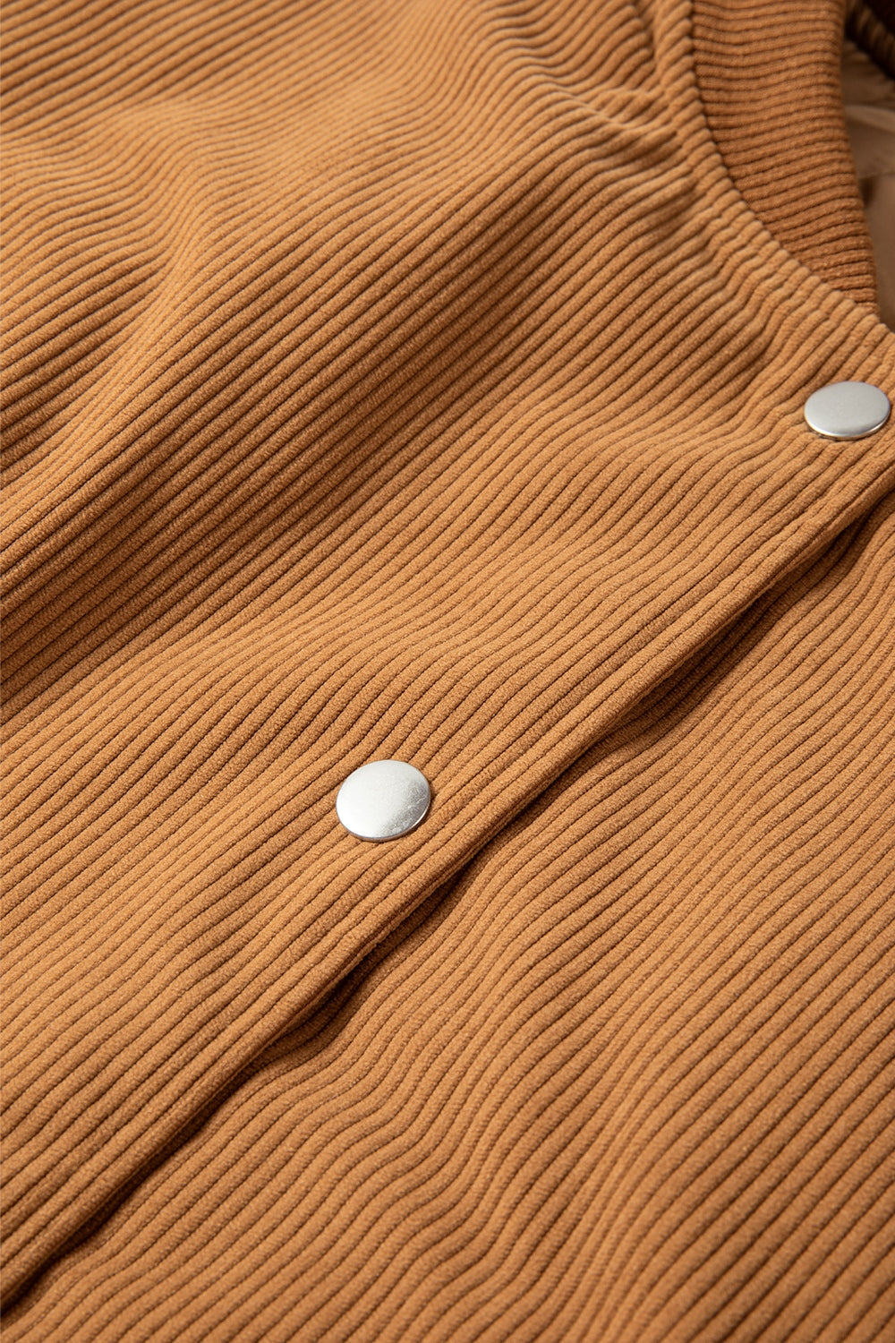 Terracotta corduroy bomber jacket detail with silver snap buttons.