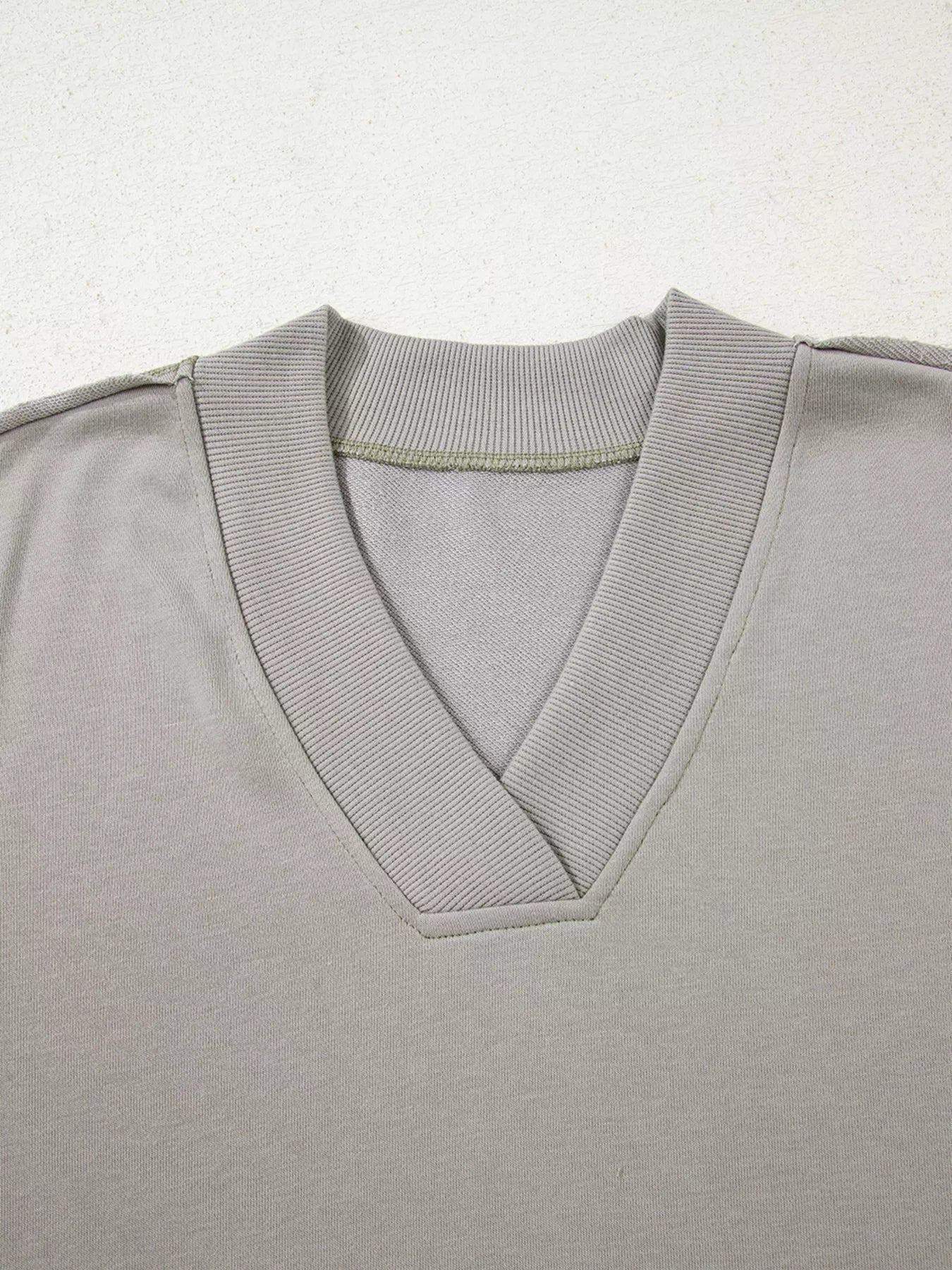 Gray v-neck sweatshirt with ribbed collar and cuffs, featuring subtle Aztec embroidery detail.