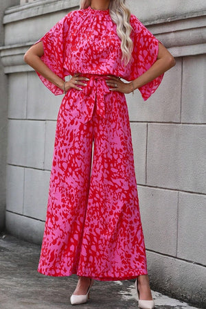 Crimson splatter tie-waist palazzo jumpsuit with wide sleeves and flowing wide-leg pants.