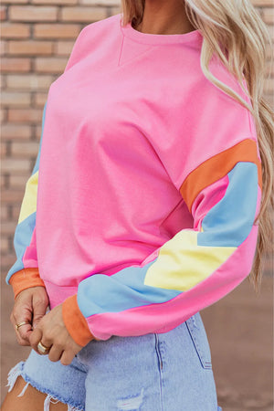 Colorblock sleeve crewneck sweatshirt in fuchsia pink with colorblock sleeves in orange, blue, and yellow.