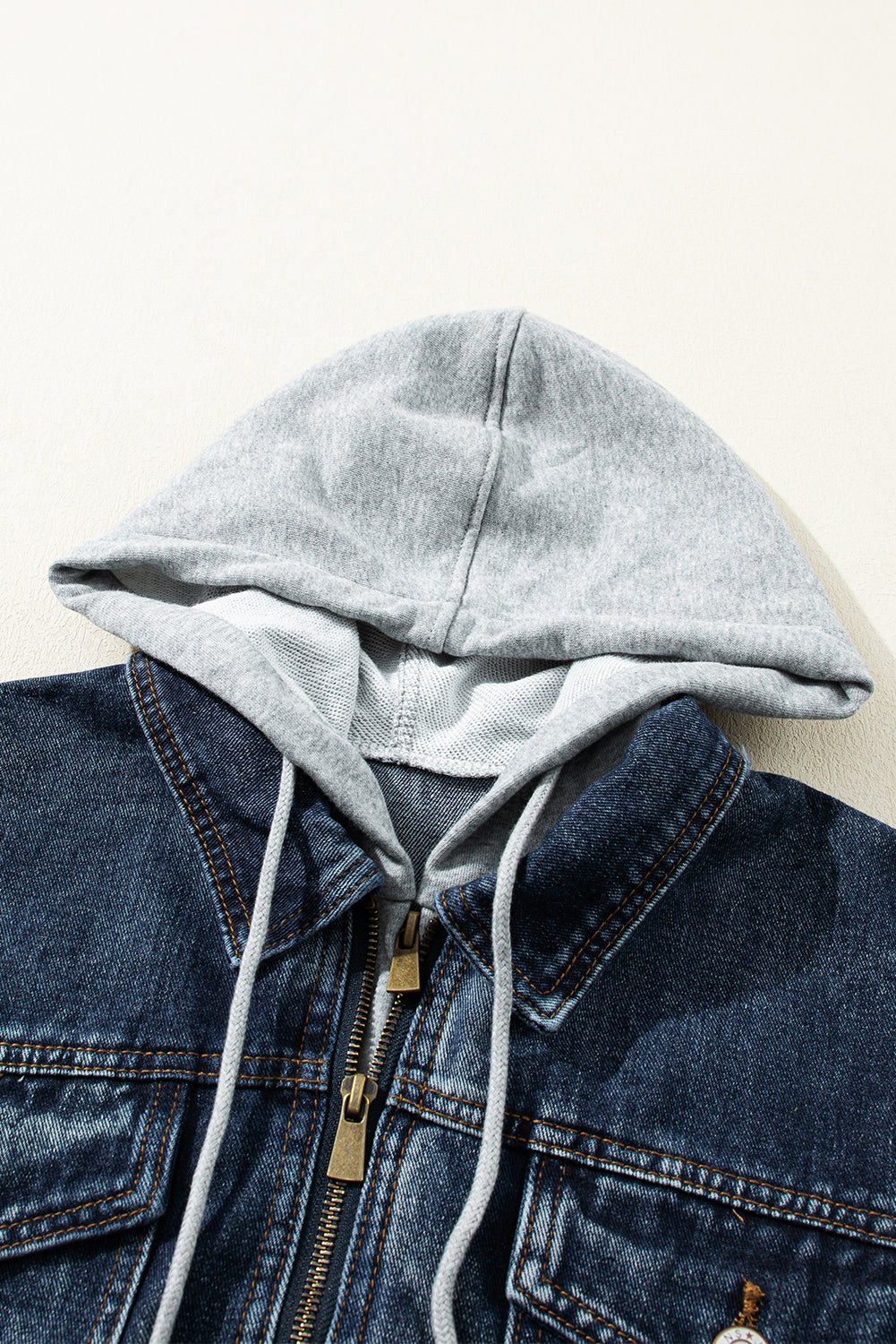 Dark blue denim jacket with grey hooded layer and zipper closure.