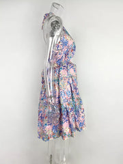 Halter mini dress in pink with abstract blue and green leaf print, cutout sides, tiered skirt.