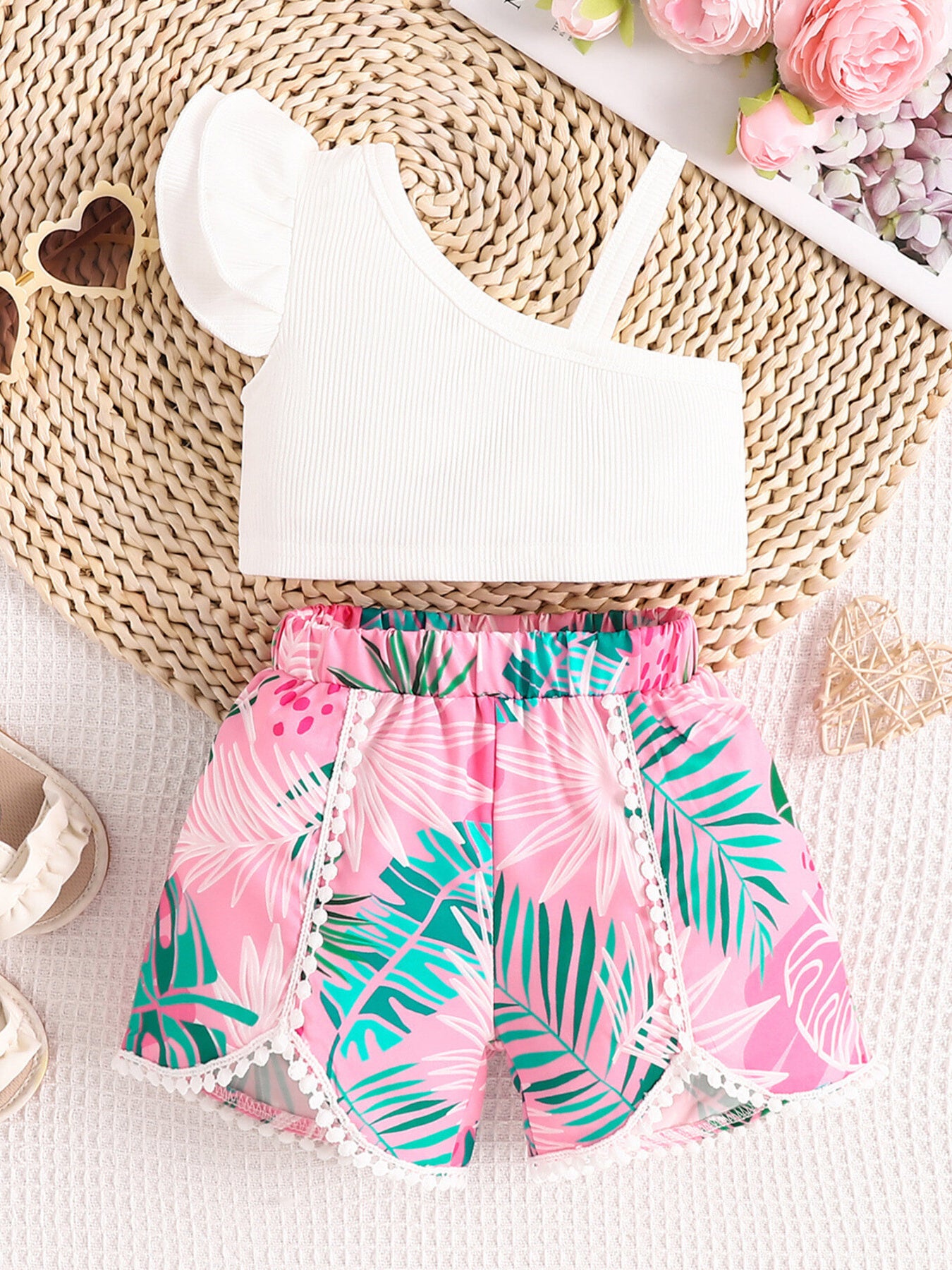 Baby girls' asymmetrical white ribbed top with ruffled sleeve and floral print pink shorts.