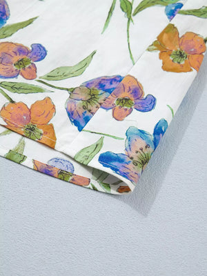 Cotton shirt with vibrant floral print, featuring orange and blue flowers with green leaves.