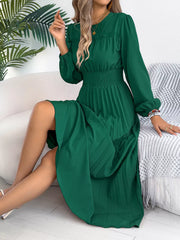 Green midi dress with ruffled neckline, smocked waist, and pleated skirt.