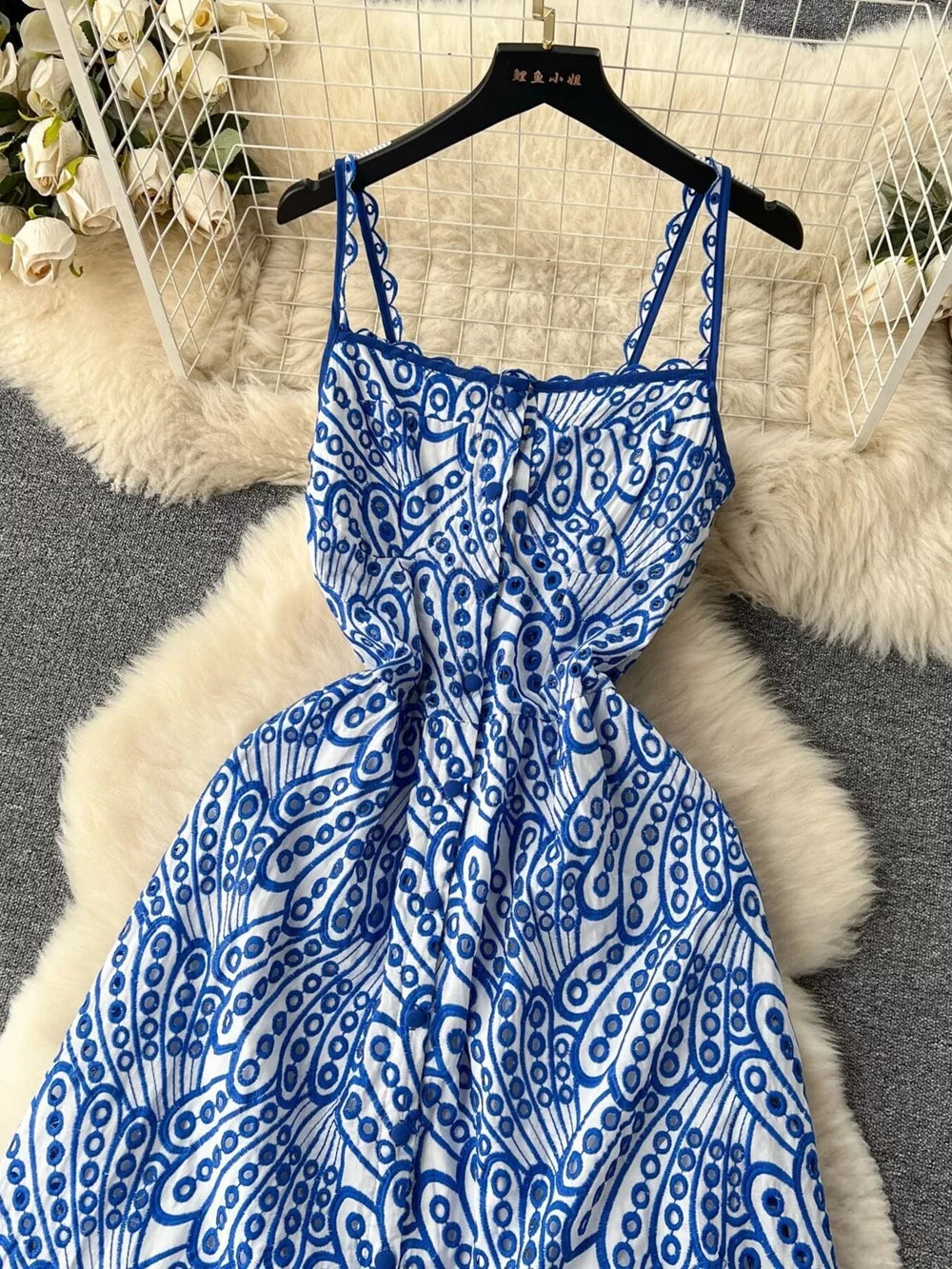 Blue and white lace-embroidered cami dress with tiered skirt and cutout details.