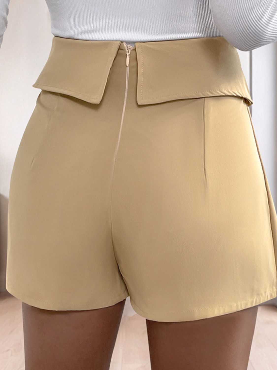 Tan collar-waist pleated skort shorts with a zip closure and a folded waistband detail.