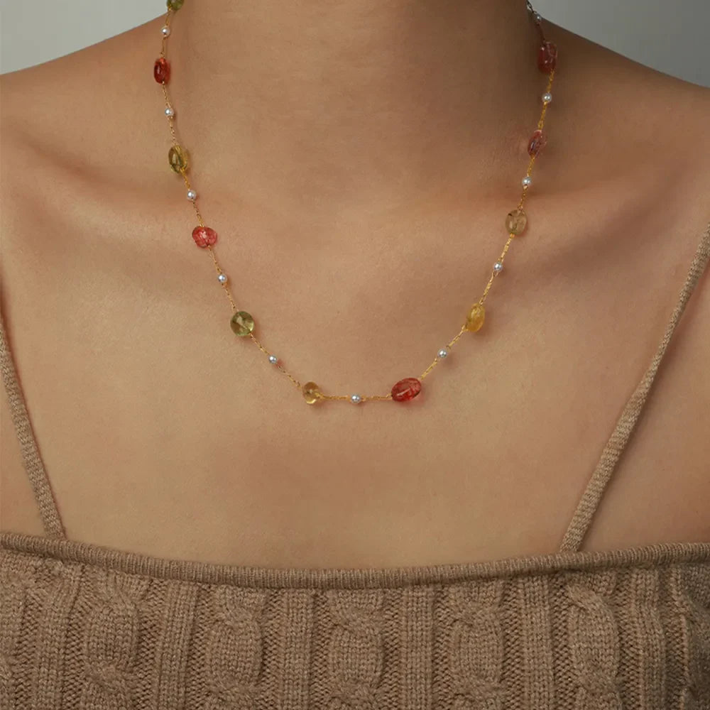 Gemstone Cascade Layered Necklace with red, green, and yellow beads and pearls on a gold chain.