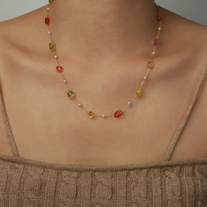 Gemstone Cascade Layered Necklace with red, green, and yellow beads and pearls on a gold chain.