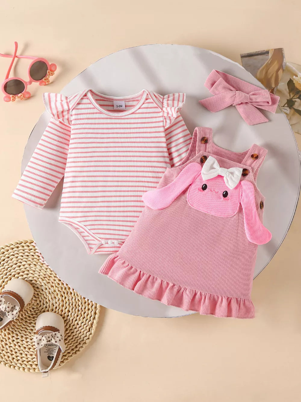 Pink striped bodysuit with ruffled sleeves and a pink bunny pinafore dress with bow and ruffles.