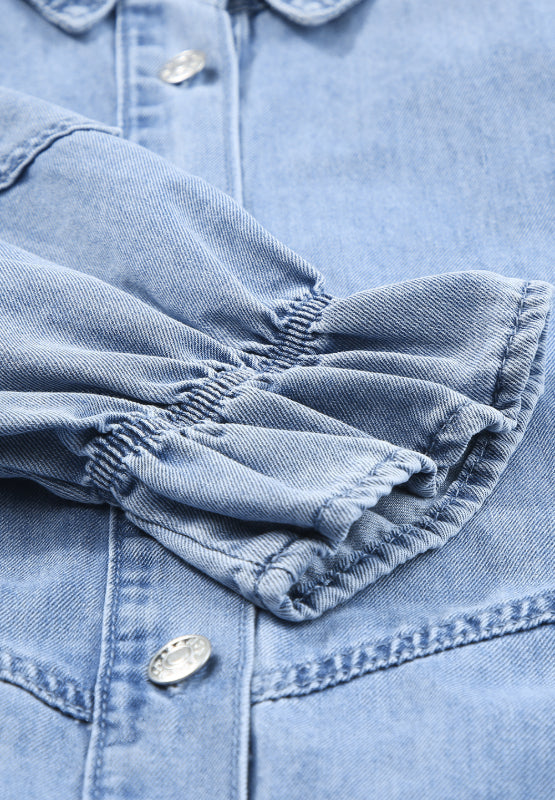 Light blue denim shirtdress with ruffled cuff detail and button closure.