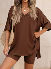 Brown V-neck two-piece set with relaxed fit top and bike shorts, styled with a straw bag.