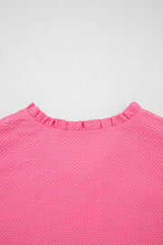 Women's pink textured blouse with a ruffled neckline