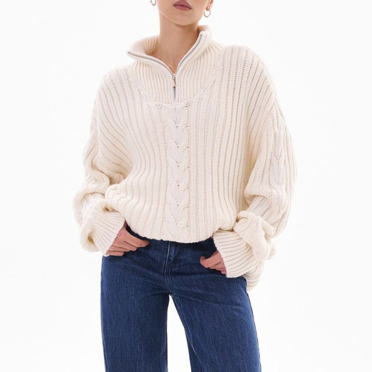 White cable knit zip-neck sweater with ribbed texture and cuffed sleeves.