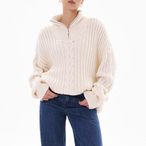 White cable knit zip-neck sweater with ribbed texture and cuffed sleeves.