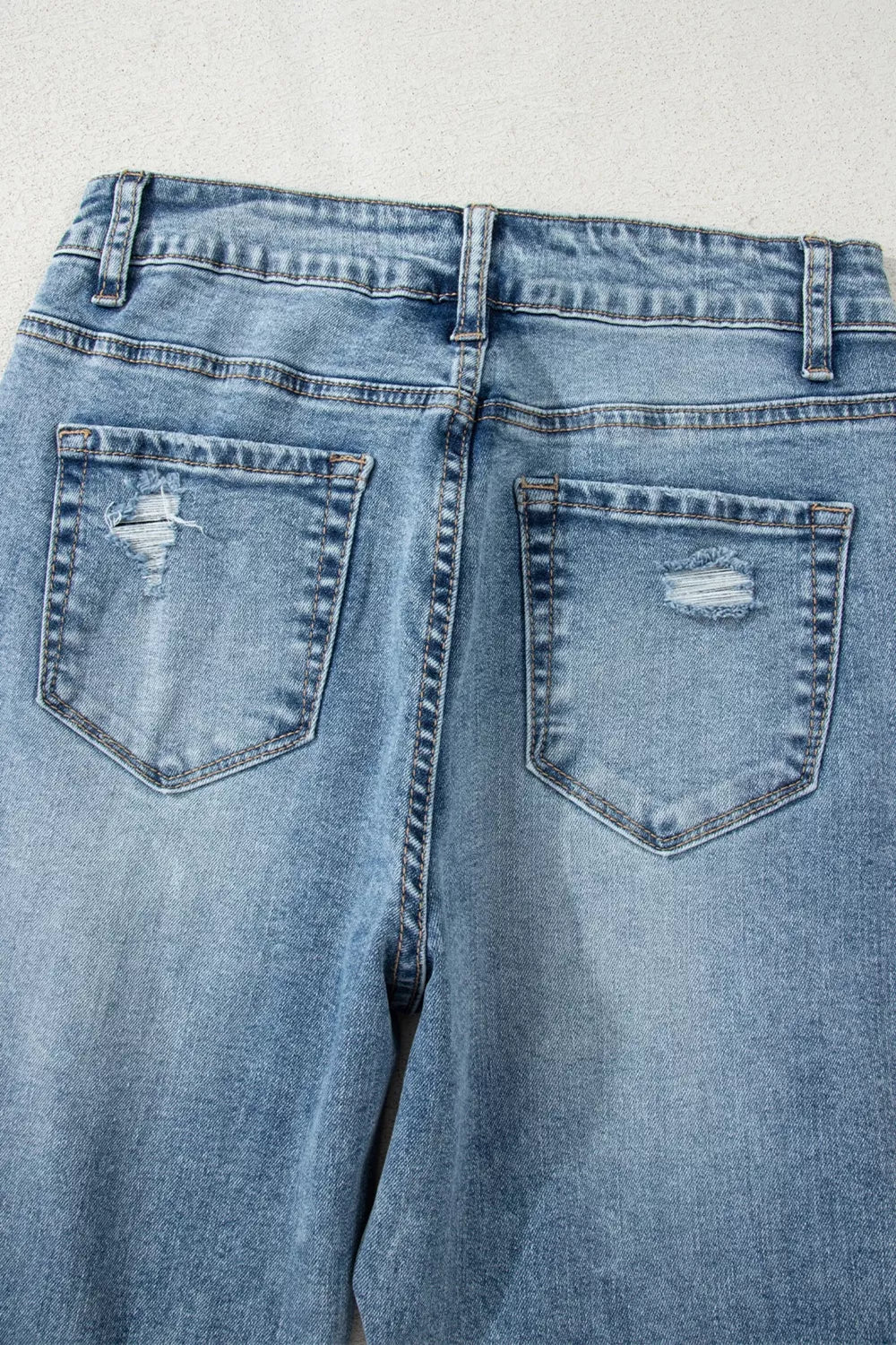 Distressed light wash denim flare jeans with open knee detail.