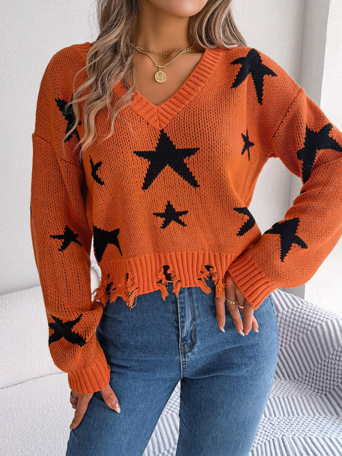 Orange star print v-neck knit sweater with distressed hem