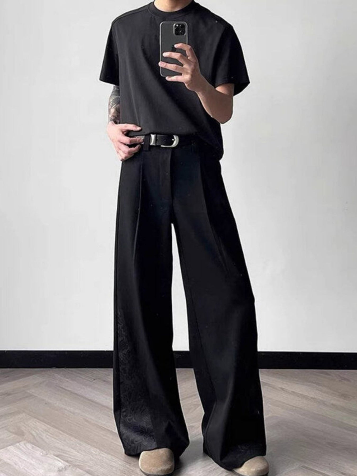 Men's black relaxed fit wide leg trousers with subtle pattern detail and a silver buckle belt.