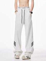 Light gray relaxed fit sweatpants with drawstring and black side stripes.