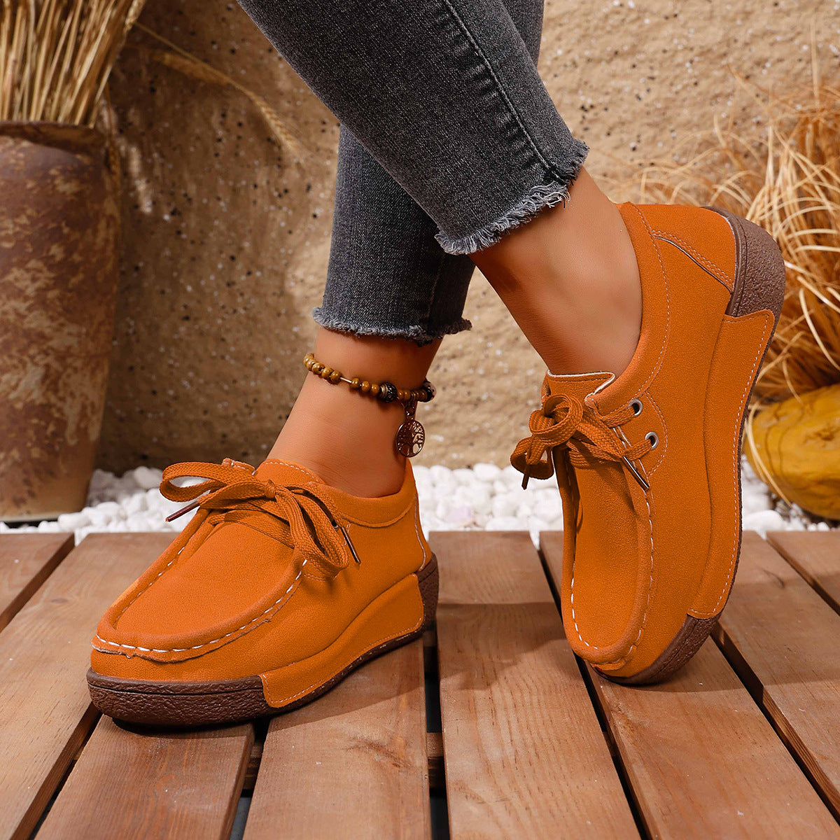 Orange lace-up moccasin style sneakers with contrast stitching and a platform sole.