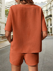Waffle knit drawstring co-ord set in burnt orange with short sleeves and shorts.