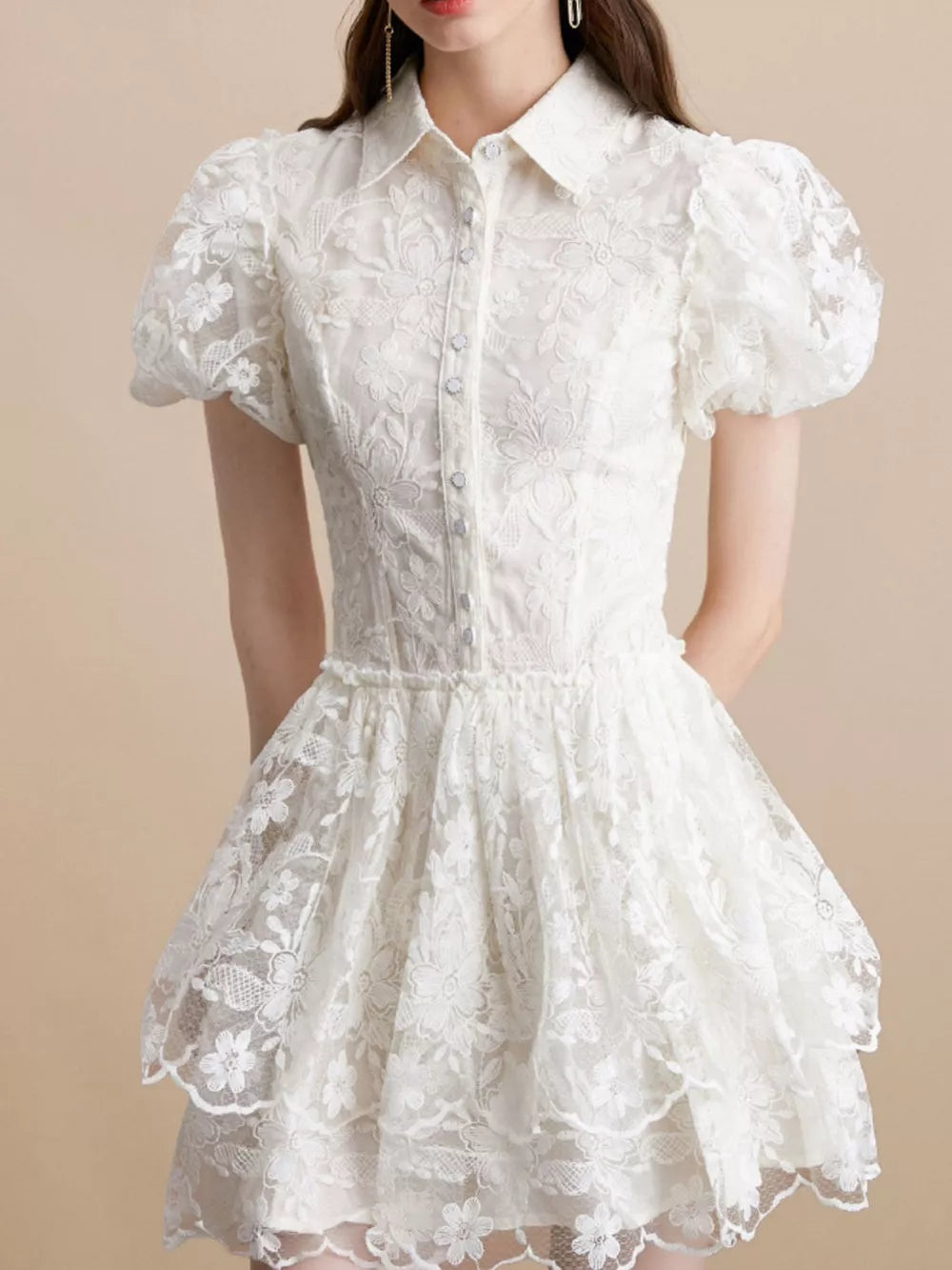 White lace mini dress with puff sleeves, button front, and tiered skirt.