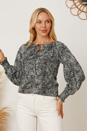 Black serpentine print blouse with tie neck and gathered sleeves.