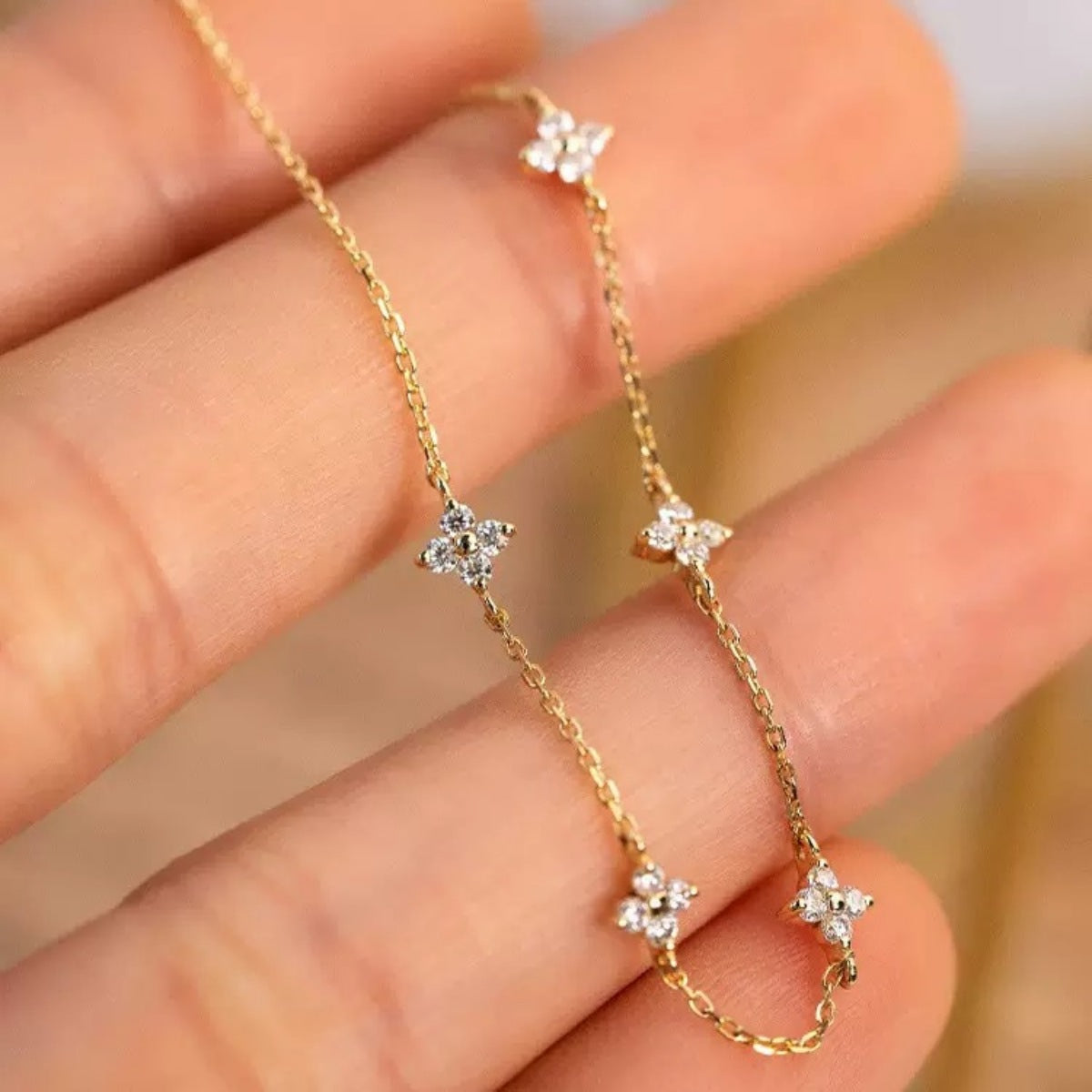 Gold delicate bracelet with four-leaf clover charms and crystal accents.