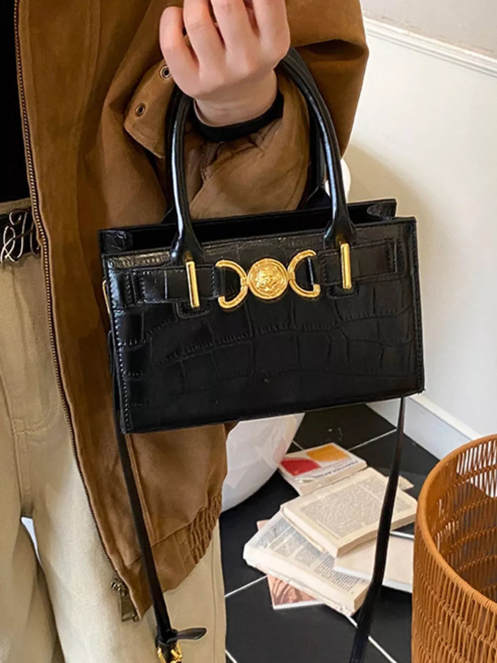 Black crocodile-textured crossbody bag with gold hardware and top handles.