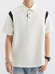 Men's beige cotton polo with black contrast shoulder panels and buttoned placket.