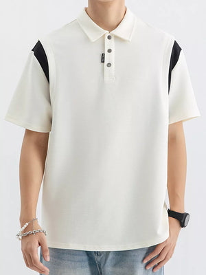 Men's beige cotton polo with black contrast shoulder panels and buttoned placket.