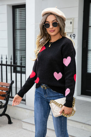 Black crewneck sweater with intarsia heart pattern in blush pink and red.