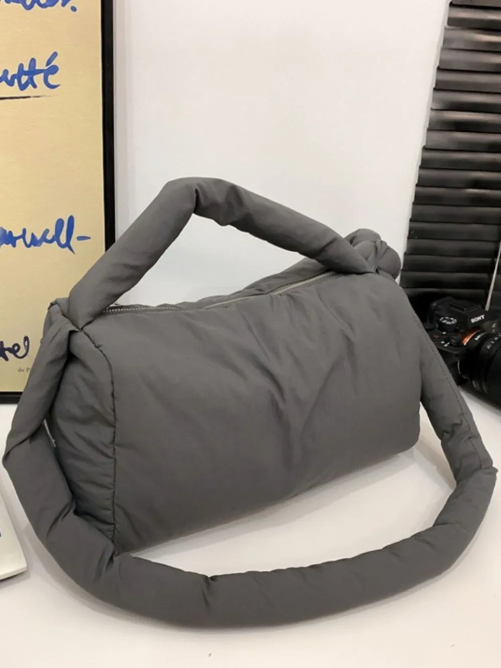 Padded knot shoulder bag in dark gray with a puffy, casual style.