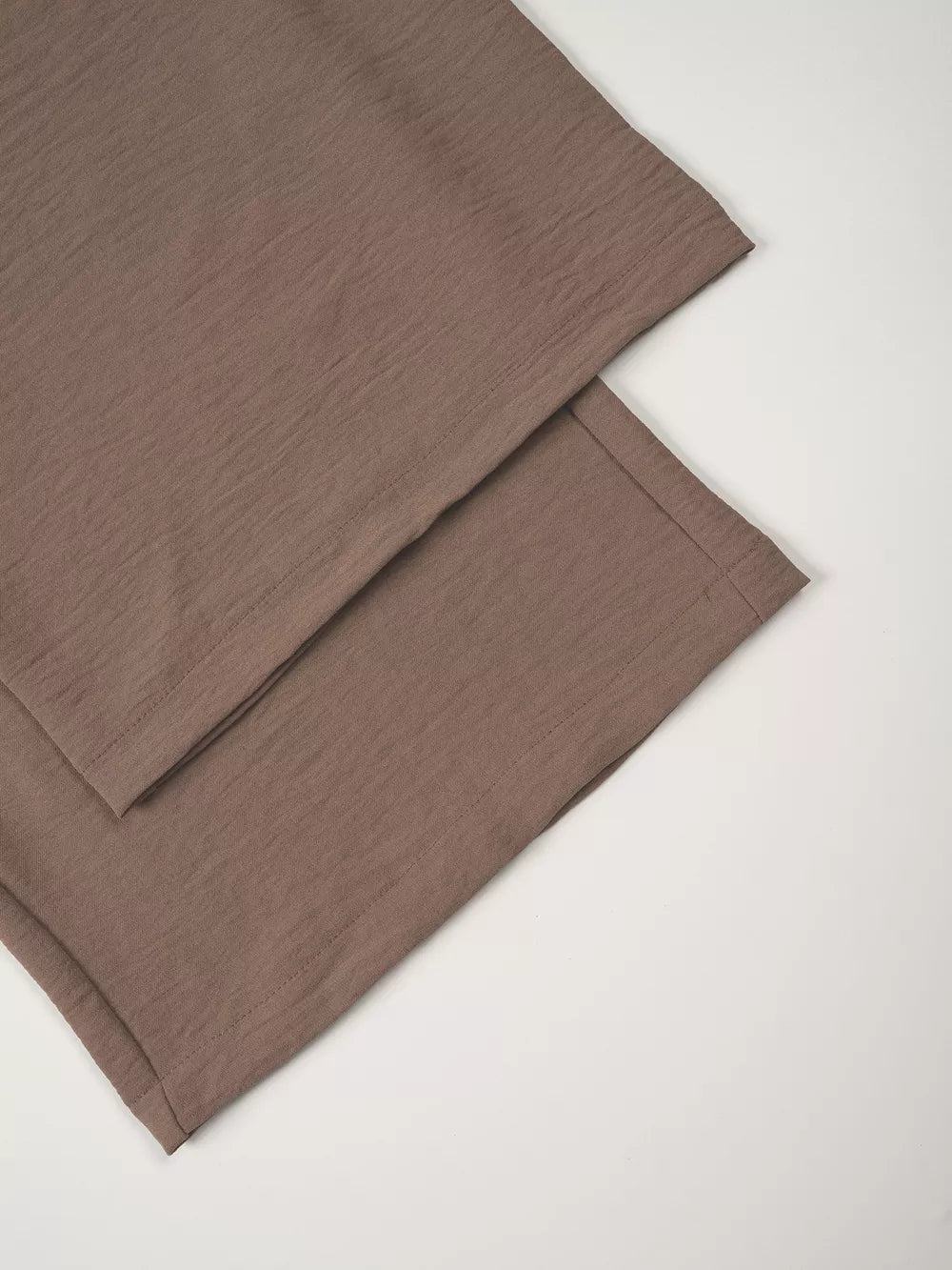 Taupe cropped vest and wide-leg pants ensemble with textured fabric detail.